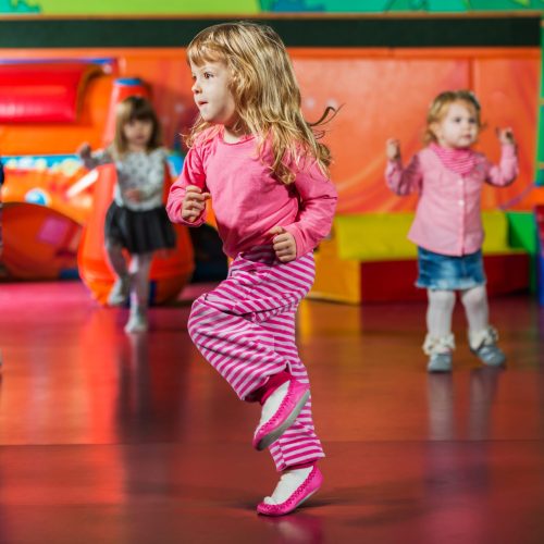 Cute kids dancing in the playroom. Focus is on foreground.